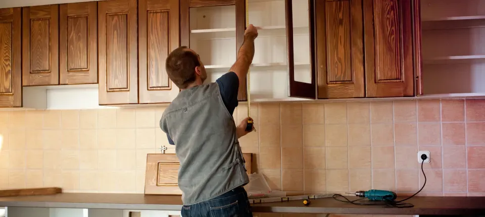 a man taking measurements in a kitchen